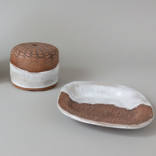 Two ceramic containers with a cracked texture on a gray background