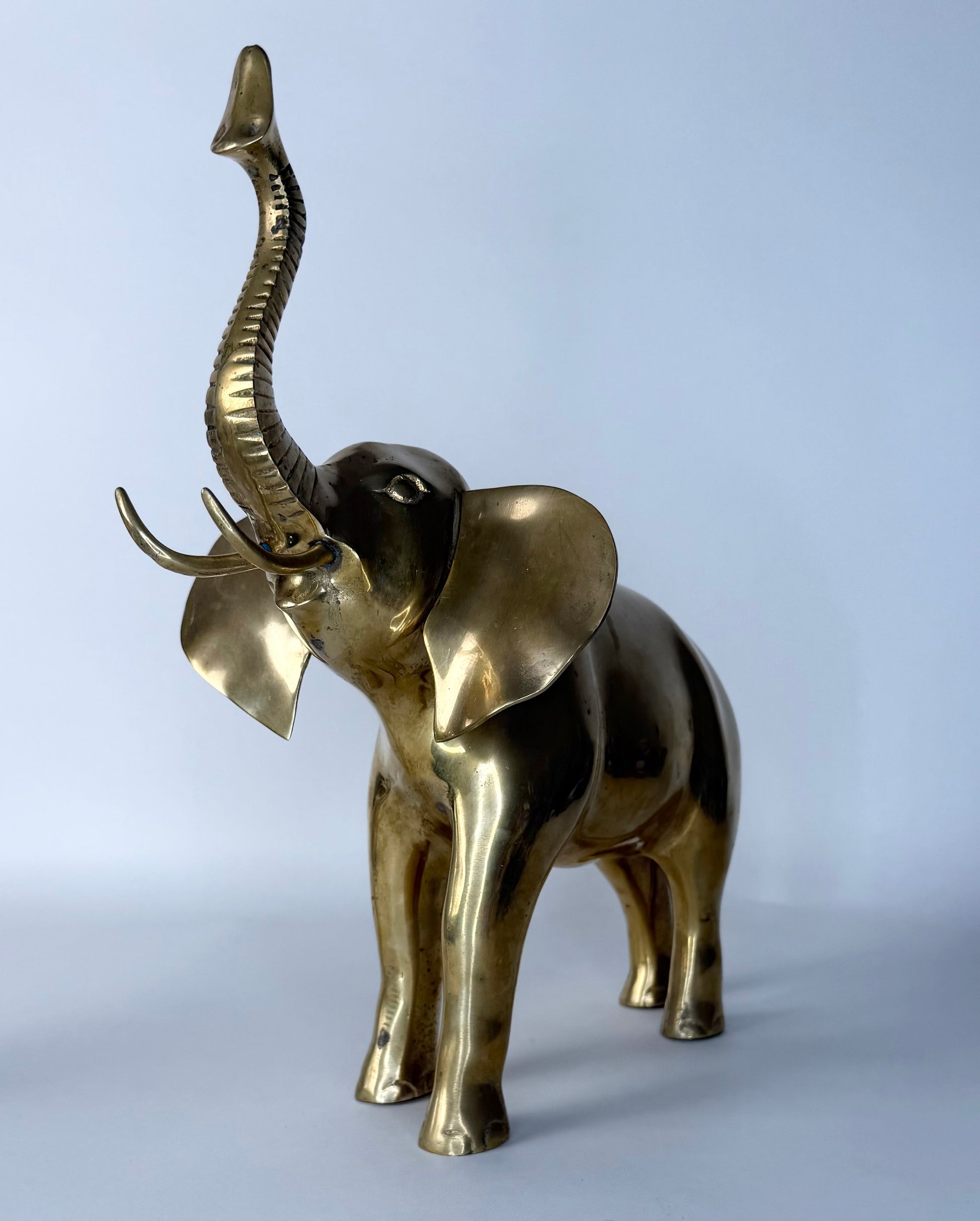 Brass elephant statue on a light gray background