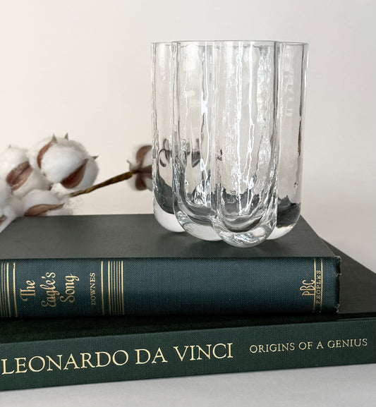 Clear glass vase on top of two books with a white background
