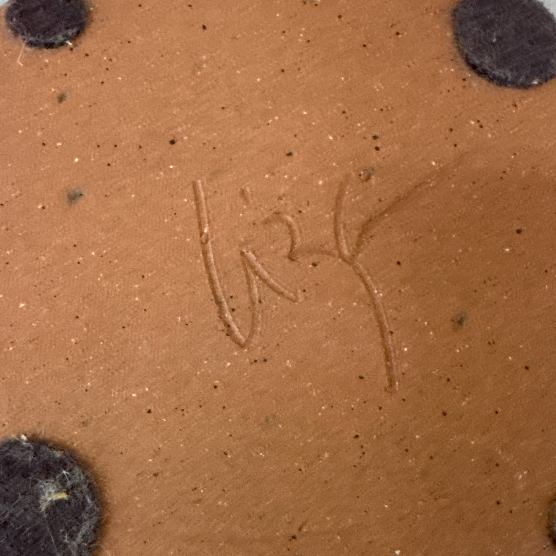 Close-up of a brown ceramic item with dark specks on a beige background