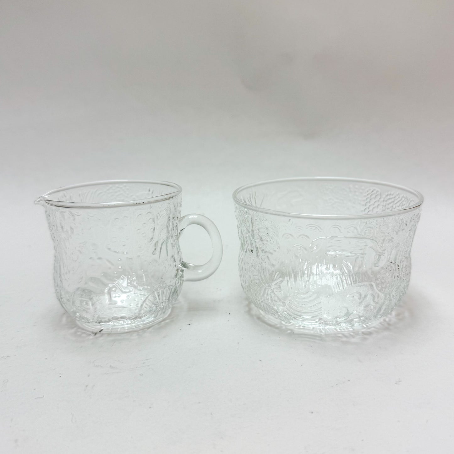 Two clear glass cups with textured design on a white background