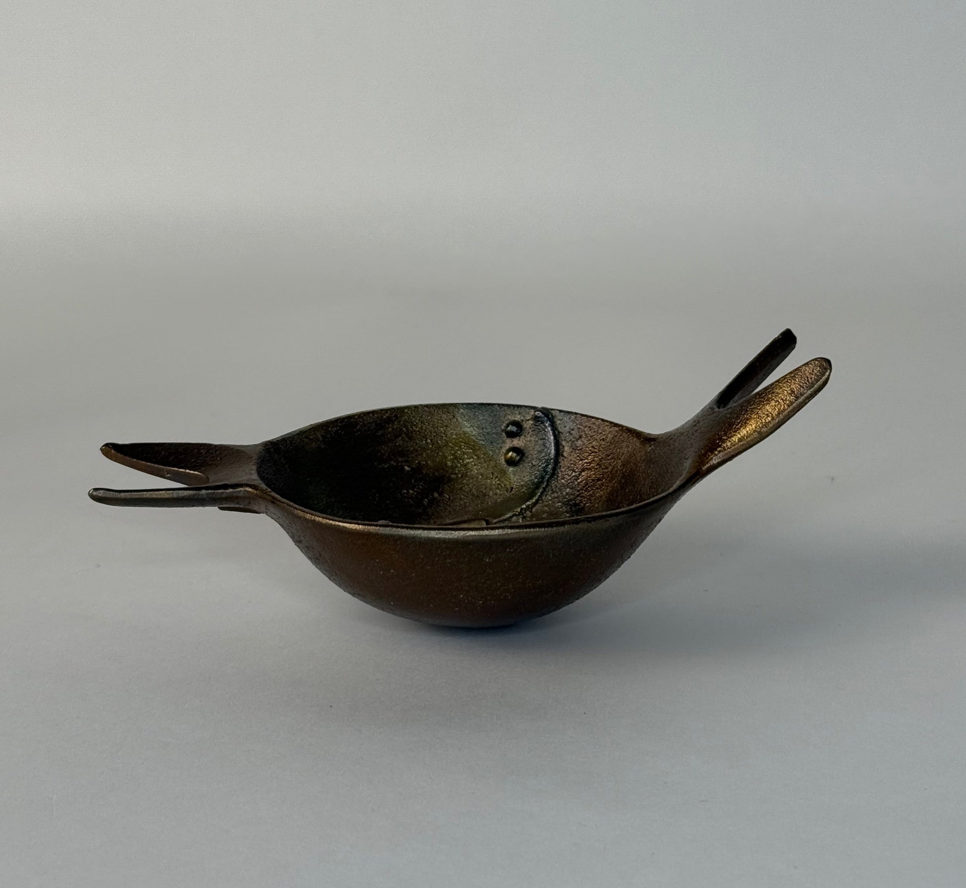 Bronze bowl with handles on a gray background